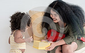 African mother giving gift box to her little daughter at home