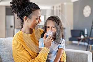 African mother helping child use nebulizer aerosol