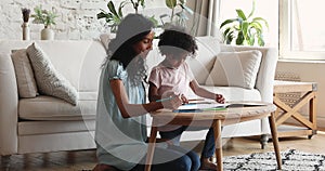 African mother and preschool daughter drawing with colored pencils