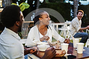 African mother and son eating food truck food outdoor - Focus on senior woman face