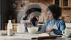 African mother teaches daughter to cook in kitchen