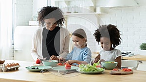 African mum two daughters cutting fresh vegetables preparing salad