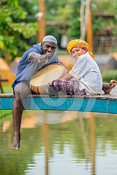 African muslim man and asian muslim boy having fun play rabana drum together