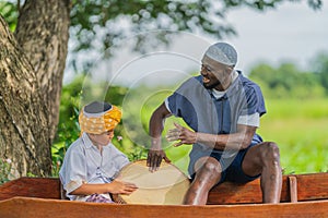 African muslim man and asian muslim boy having fun play rabana drum together