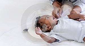 African newborn baby is 2 months old lying on a white bed smiling happily