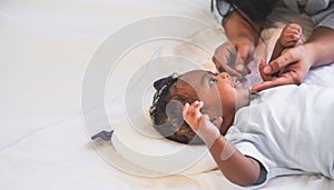 African newborn baby is 2 months old lying on a white bed smiling happily When he is looking at his mother