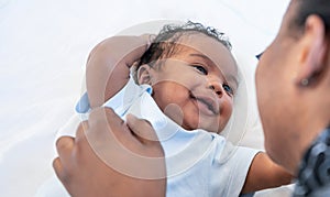 African newborn baby is 2 months old lying on a white bed smiling happily When he is looking at his mother