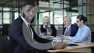 African office worker looking camera, business partners talking on background