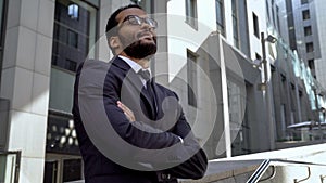 African office worker standing near modern office building, getting promotion