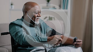 African old man elderly grandfather sitting in wheelchair measuring high low blood pressure mature male patient at home