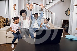 African parents playing video games on laptop with kids
