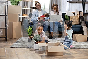 African parents with three kids using laptop at new flat