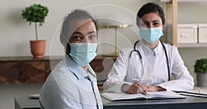African patient Indian therapist wear face masks looking at camera