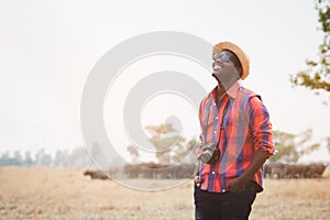 African photographer carries a camera and travels happily in Safari Africa with herds of buffalo in the background