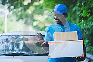 African postal delivery courier man using smart phone and delivering package