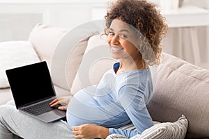 African pregnant lady using laptop with blank screen