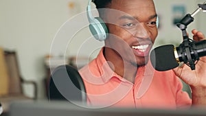 African radio presenter talking with a microphone in his home studio with headphones and a laptop. Happy black man