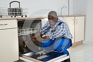 African Repairman Repairing Dishwasher