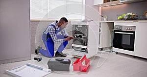 African repairman repairing dishwasher appliance