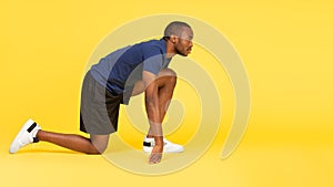 African Runner Guy Standing In Crouch Start Position, Yellow Background