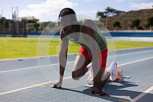 African runner in starting position on athletics track