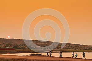 African rural people returning from work, with sunset. Sumbe. An