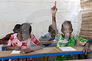 African School Children Raising Their Hands during Lesson