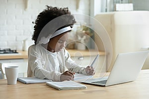 African schoolgirl in headphones using laptop do homework at home