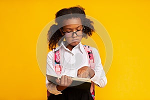 African Schoolgirl Learning To Read Holding Book Standing In Studio