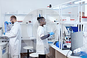 African scientist using glass flask in sterile microbiology laboratory
