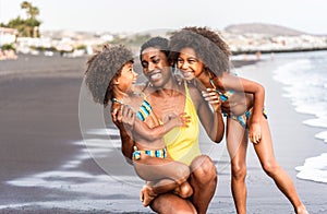 African sisters daughters on the beach with smiling mother - Black family people having fun on summer time - Vacation, travel and
