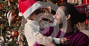 African son hugs father family posing against Christmas tree background