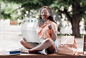 african student girl in earphones with laptop