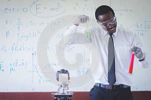 African teacher is doing science experiments inside the classroom with a  scientific equations in background