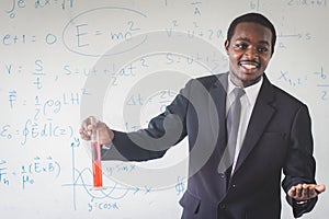 African teacher is explaining science lessons inside the classroom with a  scientific equations in background