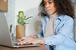 African teen girl distance learning online watching webinar on laptop computer.