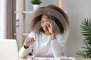 African teen girl rubbing eyes tired from computer holding glasses