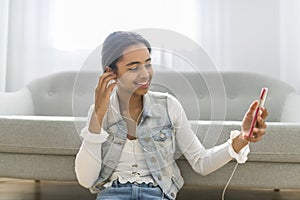 African Teen Girl Sit On Couch At Home using cellphone with earphone