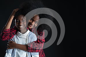 African teen siblings boy and girl hugging with smiley face on black background