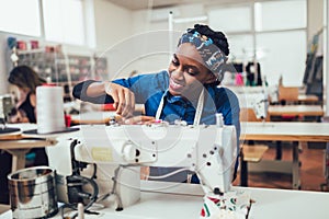 African textile worker sewing on production line. Dressmaker woman working with sewing machine