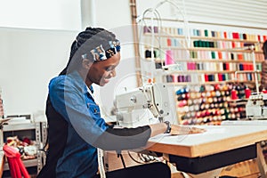 African textile worker sewing on production line. Dressmaker woman working with sewing machine