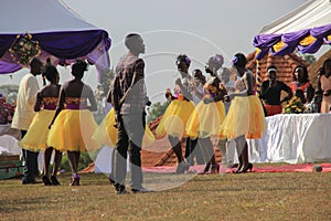 African wedding party in the park with beautiful girls dancing in traditional dresses with yellow skirts and the leading of the ce