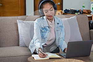 African woman, American, using laptop computer and wearing headphones for online learning