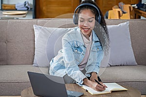 African woman, American, using laptop computer and wearing headphones for online learning