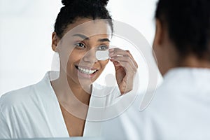 African woman applies patches to reduce dark circles