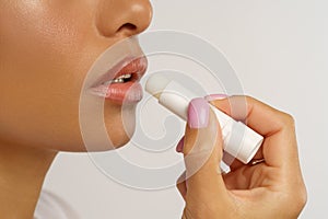 African woman apply hygienic balsam lipstick for lips moisturizing and protection from cold and wind