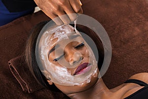 African Woman Applying Facial Mask In Spa