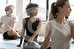 African woman with associates practicing yoga seated in lotus pose