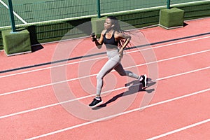 African woman athlete running on racetrack. Sportive black female training jog on stadium sprinting