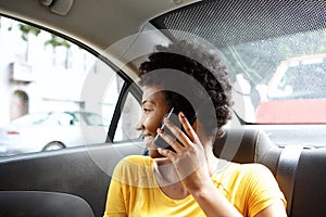 African woman on back seat of car making a phone call